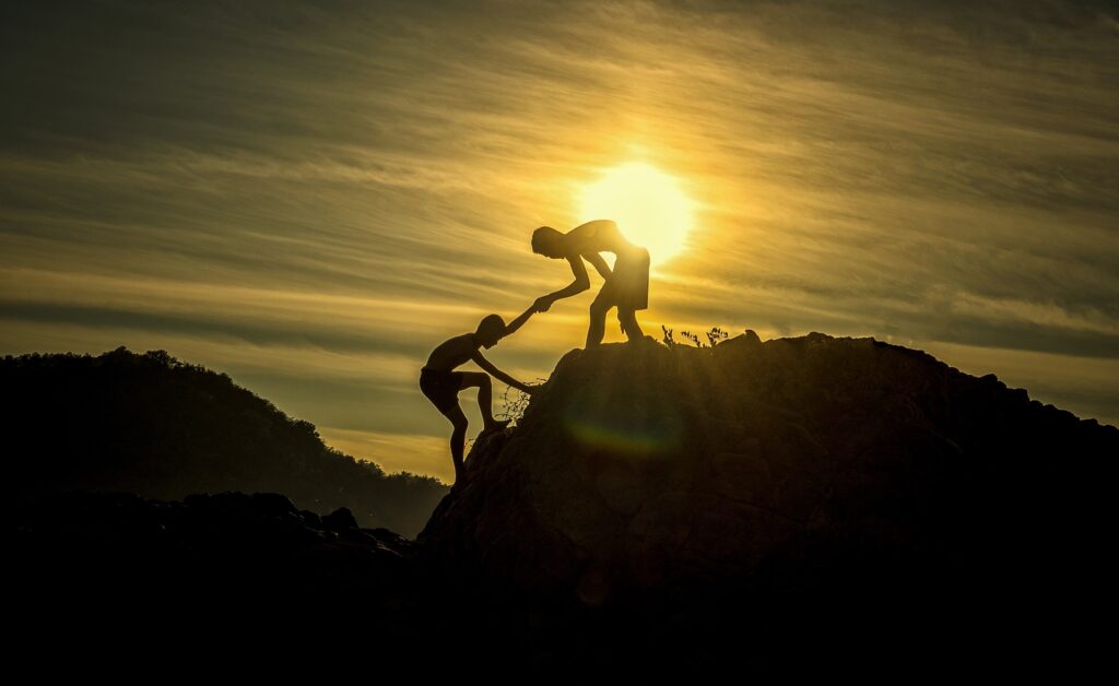 man helping another to climb up hill
